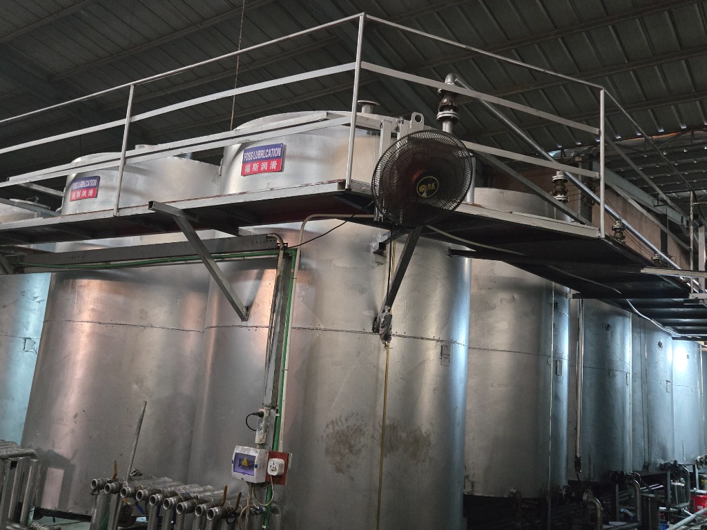 Automated stainless steel blending kettles with FOSS LUBRICATION 福斯润滑 signage and piping manifolds