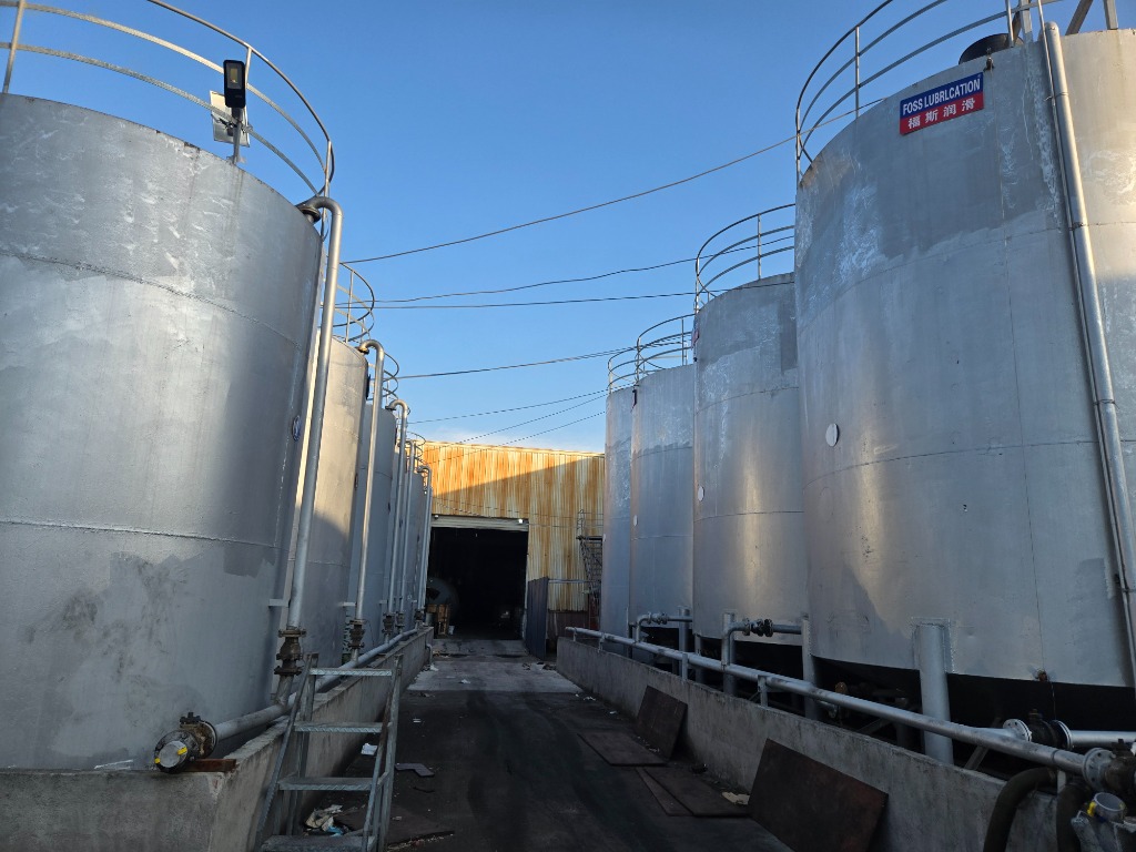 Outdoor bulk base oil silo farm with secondary containment bund wall and transfer pipelines